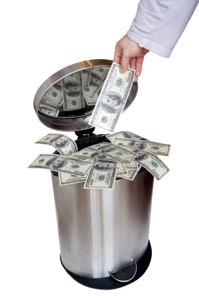 Wasting money - dollar bills in trashcan
